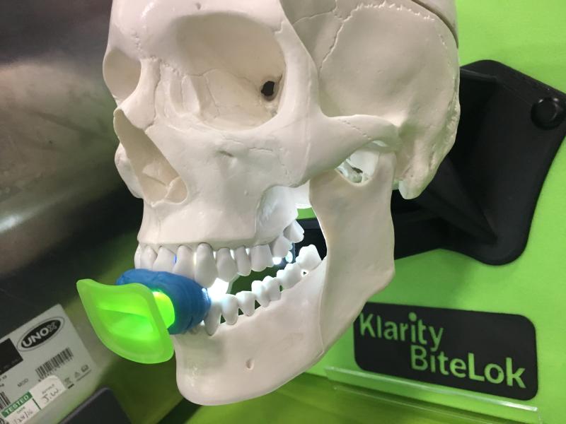这是一种新的放射肿瘤学舌固定装置，以防止头部或颈部肿瘤位置在治疗过程中的移动或变化。Klarity BiteLok设备正在2019年美国医学物理学家协会(AAPM)会议的展览地板上展出。它使用标准的牙科腻子模具到患者的嘴，和一个夹子，以保持安装到位，作为头部固定面具的成型。口片可从口罩上取下清洗。