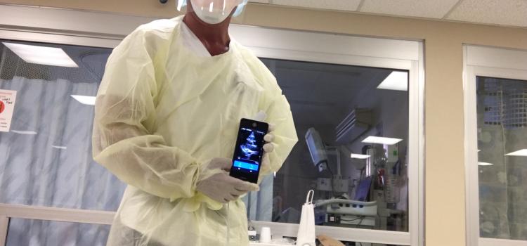 那不勒斯社区医院心脏成像主任Bill Shirkey展示了一名COVID-19患者的即时心脏超声扫描。他在隔离室的床头使用了GE Healthcare的Vscan设备。